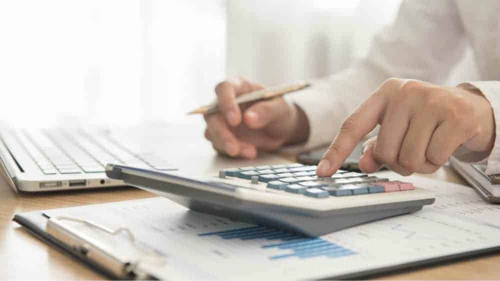 Businessman using calculator next to laptop