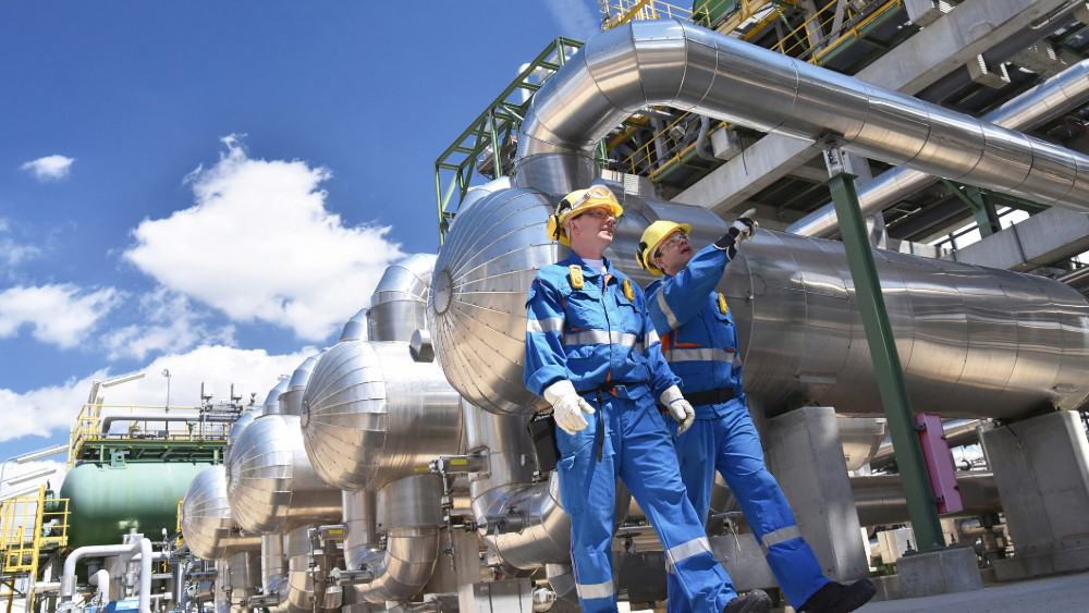 Group of industrial workers in a refinery - oil processing equipment and machinery